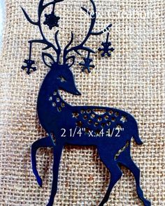 a blue metal deer with stars on it's antlers is sitting on a piece of fabric