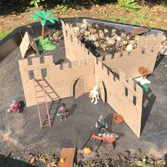 a castle made out of cardboard sitting on top of a cement ground next to trees