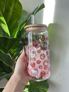 a hand holding up a hello kitty glass jar