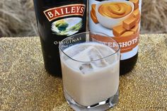 two bottles of bailey's beer next to a glass filled with ice and liquid