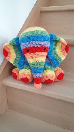 a crocheted stuffed elephant sitting on the stairs