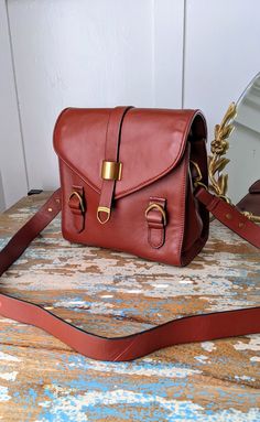 New without tags vintage Rudsack brick red leather messenger bag with brass metal accents. Tan ultrasuede lining with a larger zipped pocket and two small side pockets. Adjustable shoulder strap, bonded leather with black edges. Magnetic closure. Unused condition. 9 x 9 x 4.4" Leather Satchel Backpack With Hasp Closure, Leather Shoulder Backpack With Hasp Closure, Brown Leather Saddle Bag With Hasp Closure, Retro Leather Backpack Shoulder Bag, Retro Leather Backpack-style Shoulder Bag, Leather School Bag With Hasp Closure, Travel Crossbody Saddle Bag With Hasp Closure, Crossbody Saddle Bag With Hasp Closure For Travel, Retro Leather School Satchel