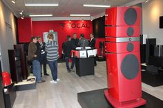 a group of people standing around in a room with speakers on the floor and red walls