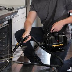 a man using a vacuum to clean an oven