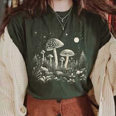 Mushroom Shirt, Celestial T-shirt, Magical Fungi Shirt, Moon Phases Stars, Goblincore Aesthetic, Cottagecore, Dark Academia 📣 INFORMATION * All shirts are UNISEX * 100% Airlume combed and ringspun cotton (fiber content may vary for different colors) * Wash and dry normally (on cool for best results) 👕 SIZING * For an oversized fit, select two or three sizes up from your normal size * Model is wearing size L * Sizing runs true to size * Most women find their typical size works best, since they Mushroom Shirt Aesthetic, Unisex Cottagecore Outfits, Dark Cottagecore Summer Outfits, Fairy Grunge Crew Neck T-shirt With Graphic Print, Cute Collared Shirts, Green Goblincore Cotton Top, Green Cotton Goblincore Top, Fall Goblincore Crew Neck T-shirt, Fairy Grunge Cotton T-shirt With Graphic Print