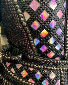 the back of a black leather jacket with iridescent studs and rivets