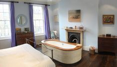 a large bath tub sitting in the middle of a bedroom next to a bed and dresser