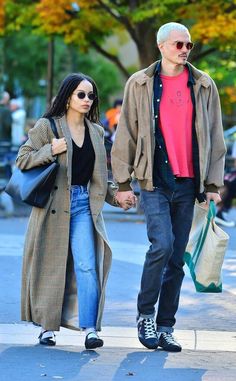 a man and woman are walking down the street holding hands with each other while carrying shopping bags