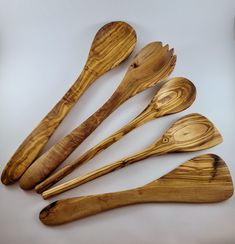 five wooden spoons and two forks on a white surface