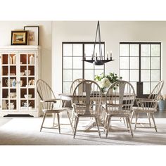 a dining room table with chairs and a chandelier hanging from the ceiling in front of windows