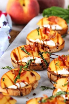 grilled peaches with goat cheese and basil on a sheet of parchment paper next to fresh fruit