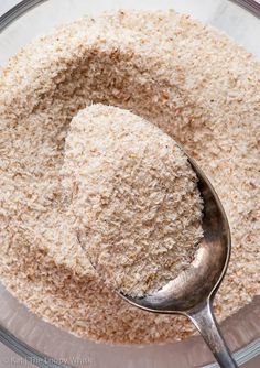 a spoon in a glass bowl filled with brown and white rice flakes, ready to be cooked