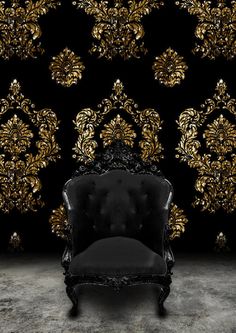 a black and gold chair sitting in front of a wallpaper covered with golden flowers