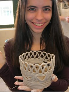 a woman is holding a white vase in her hands and smiling at the camera,