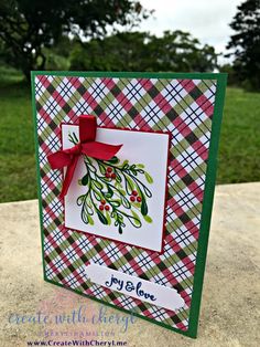 a close up of a card with a red bow on the front and green plaid background