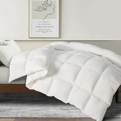 a white comforter sitting on top of a bed next to a pillow and blanket