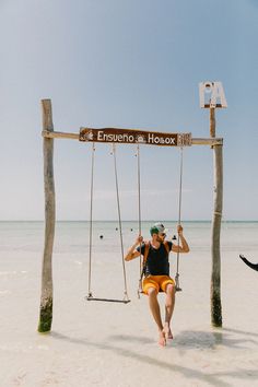 a man sitting on a swing at the beach