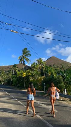 two women walking down the street in front of power lines and palm trees on a sunny day