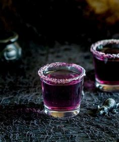 two glasses filled with purple liquid sitting on top of a table