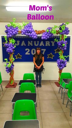 a woman standing in front of a balloon arch with grapes on it and the words mom's balloon