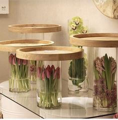 vases filled with flowers sitting on top of a glass table next to a mirror