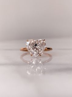 a heart shaped diamond ring on a white surface