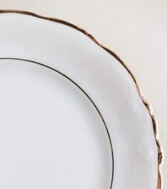 an empty white plate with gold trim around the edge