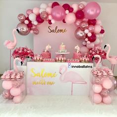 a pink flamingo themed dessert table with balloons and decorations on the wall behind it