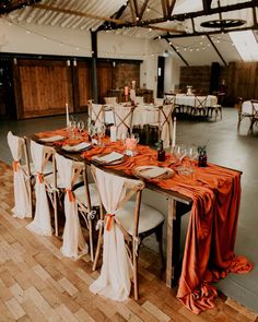 the tables are set with orange and white linens for an elegant wedding reception at the barn