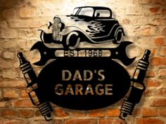 a sign that says dad's garage on the side of a brick wall with an old car