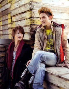 two young men sitting next to each other in front of a pile of wooden planks