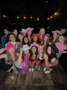 a group of women in costumes posing for a photo at night with hats on their heads