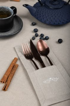 two spoons, one fork and some cinnamon sticks on a table with blueberries