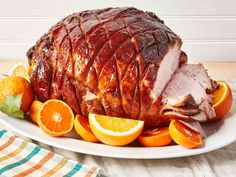 a large ham on a plate with oranges