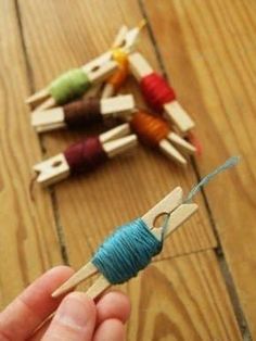 a person is holding a skewer with yarn and wooden clothes pins on it