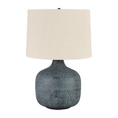 a blue ceramic lamp with a white shade on the base and a beige linen lampshade