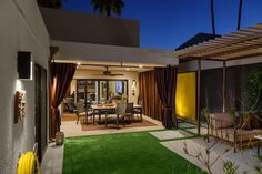 an outdoor living room and dining area with artificial grass on the lawn at night time