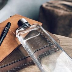 an empty water bottle sitting on top of a table next to a wallet and pen