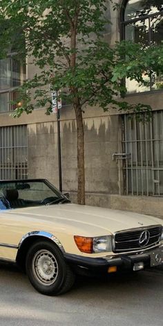 a beige mercedes benz parked on the side of the road in front of a building