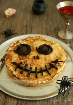 a plate topped with pancakes covered in icing next to a cup of tea and a spider