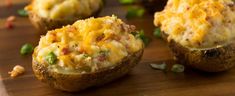 baked potatoes with cheese and green onions on a wooden cutting board, ready to be eaten