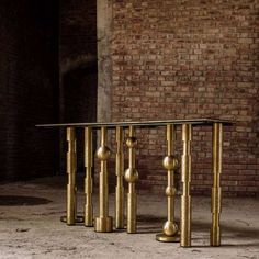 a table that has been made out of brass pipes and is sitting in front of a brick wall