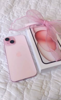 an iphone case with a pink bow sits on a bed next to a box that has the phone in it