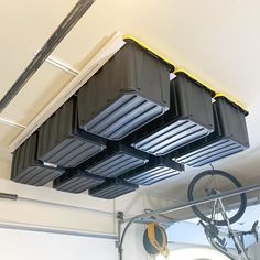 a bike hanging from the ceiling in a garage with storage bins attached to it