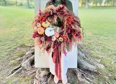 a woman standing next to a tree with a wreath on it