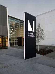 a large black sign sitting in front of a building next to a tree and walkway