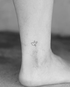 a small bird tattoo on the ankle is seen in this black and white photo,