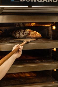 a person pulling bread out of an oven