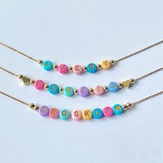 Add a burst of vibrant charm to your little one's outfit with our Bright Colorful Beads Name Necklace! This delightful piece combines the timeless elegance of dainty gold name beads with an array of eye-catching, colorful hued beads. Each letter of your child's name is lovingly crafted with precision and adorned with a captivating spectrum of colors, creating a personalized gift that will surely bring smiles. These necklaces would also make great party favors for a childs birthday party. Beads are chosen randomly and the necklace is accented with 18K gold hearts or 18K round ball beads.  Necklace chain is 18K plated and dainty.  Choose which style you would like from the drop down menu along with the length of the necklace. Necklace is packaged for gift giving. To see more Kids Necklaces c Cute Personalized Multicolor Charm Necklaces, Playful Heart-shaped Letter Beads Bracelet, Adjustable Multicolor Charm Necklace For Birthday, Adjustable Multicolor Charm Necklaces For Birthday, Adjustable Colorful Beads Necklace For Birthday, Valentine's Day Playful Beaded Jewelry, Multicolor Handmade Charm Necklace For Birthday, Playful Multicolor Personalized Charm Necklaces, Cute Multicolor Charm Necklace For Birthday