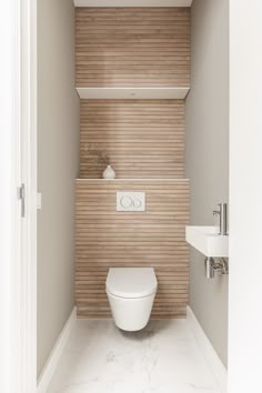 a white toilet sitting inside of a bathroom next to a wall mounted faucet